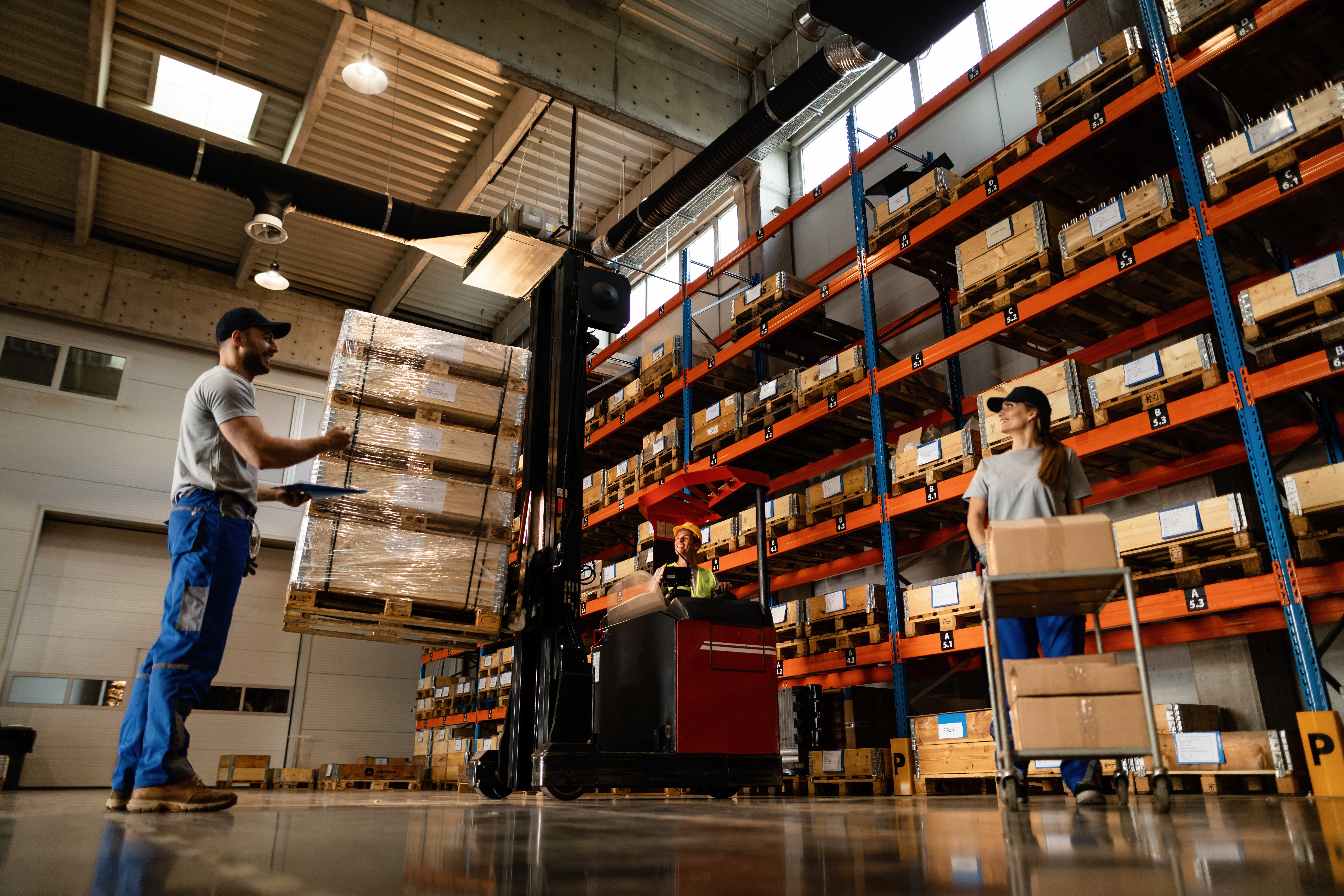 vista-de-angulo-baixo-de-trabalhadores-de-armazem-felizes-se-comunicando-enquanto-trabalhavam-com-remessa-no-compartimento-de-armazenamento-industrial